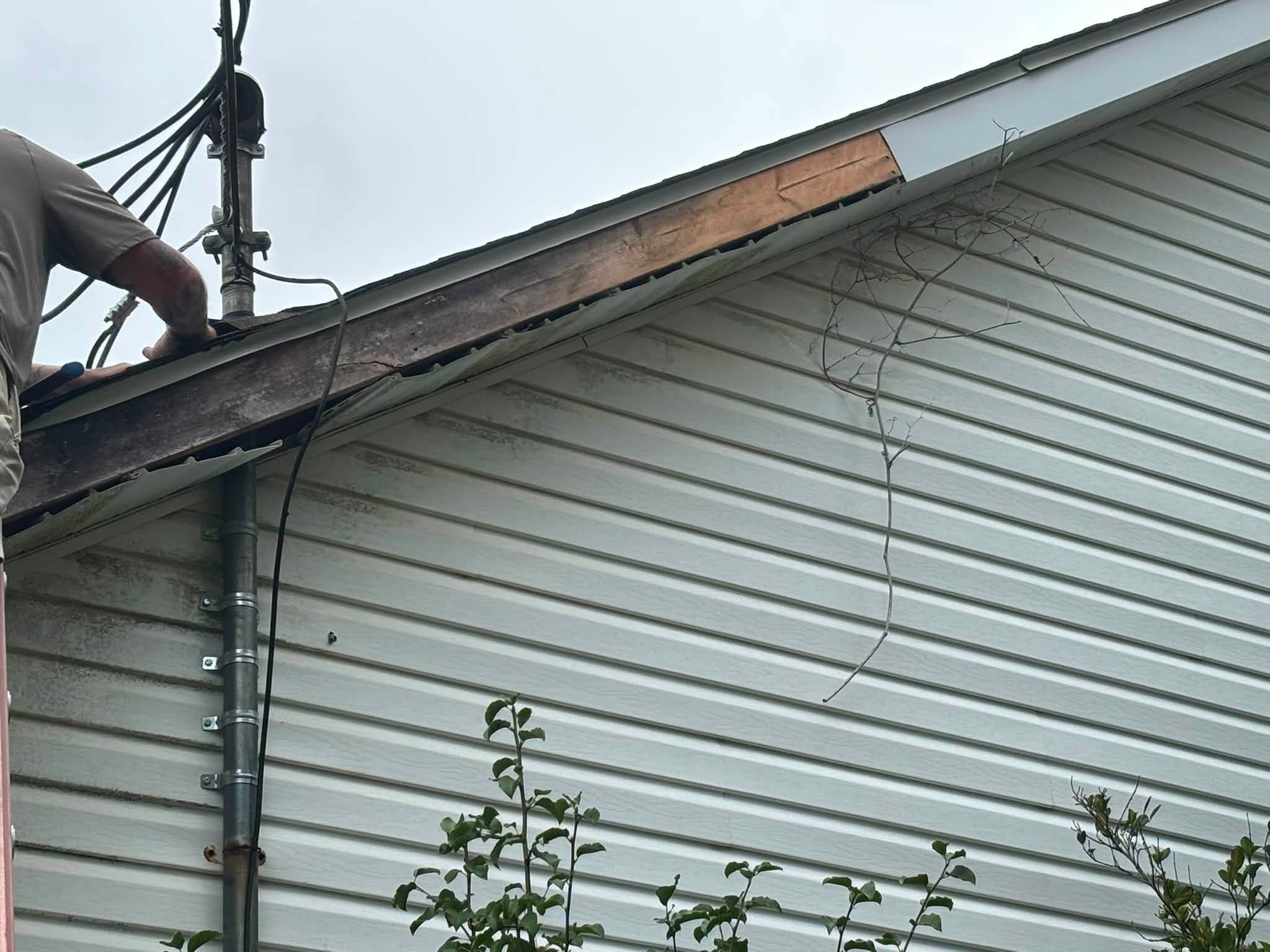 Gable end of a vinyl-sided house during fascia replacement