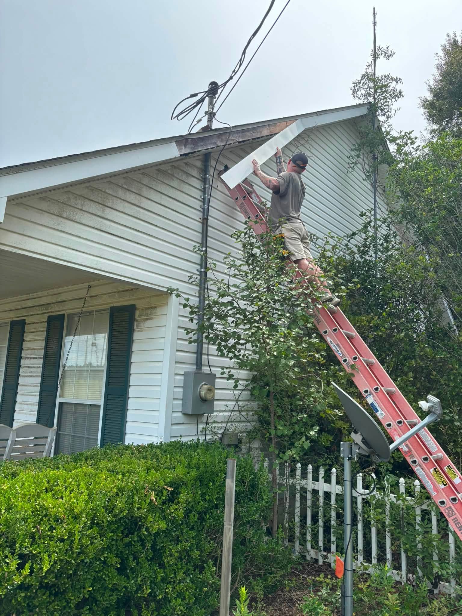 REDLINE on a ladder replacing fascia board at the peak of a gable