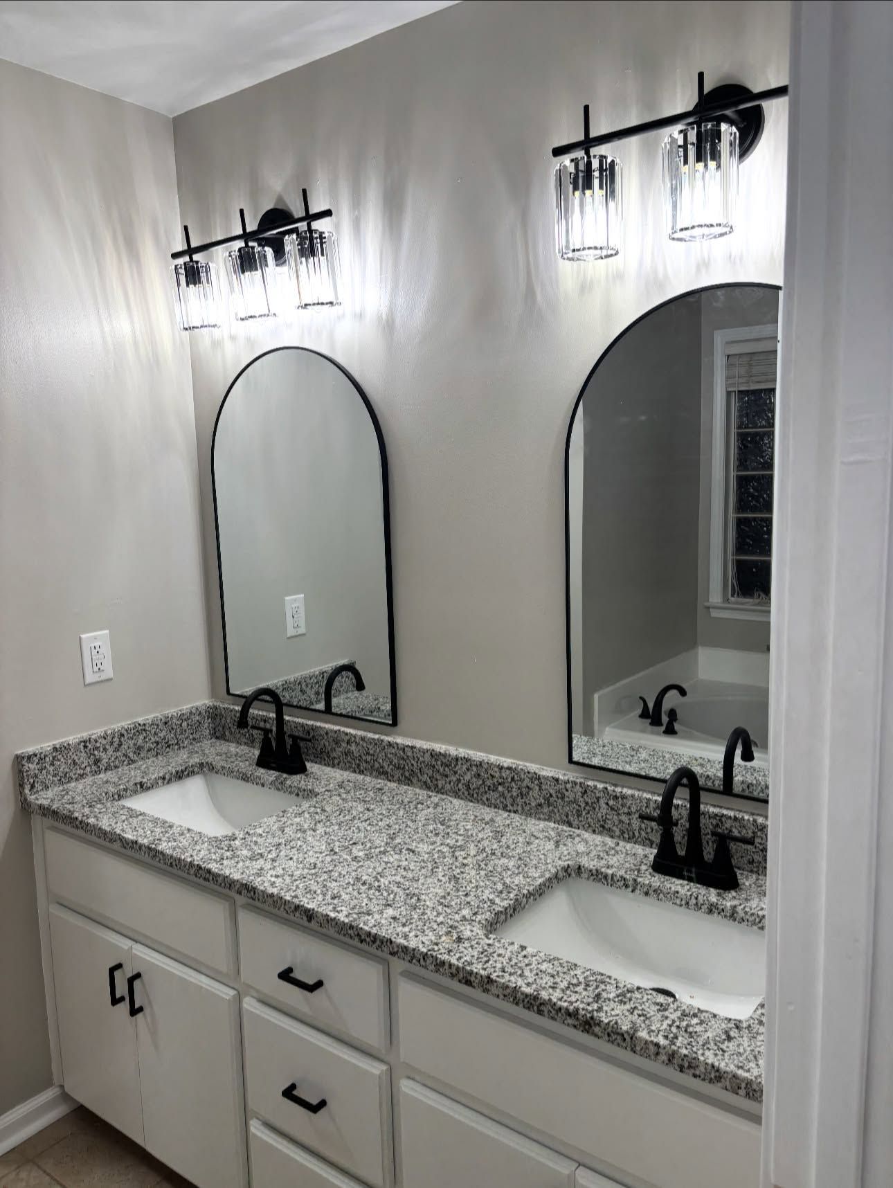Master bathroom updated by REDLINE: repainted vanity, arched black mirrors and new lights
