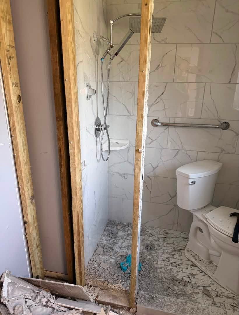 Tiled shower seen through the framing of the newly added wall